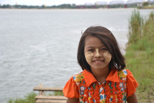 Little girl with Thanaka on her face, yellow white cosmetic paste made from bark